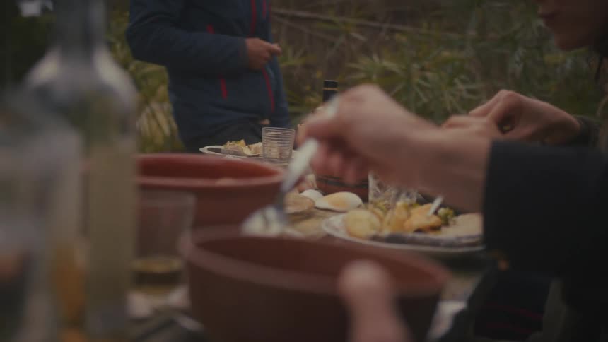 People are eating a meal on a table outside