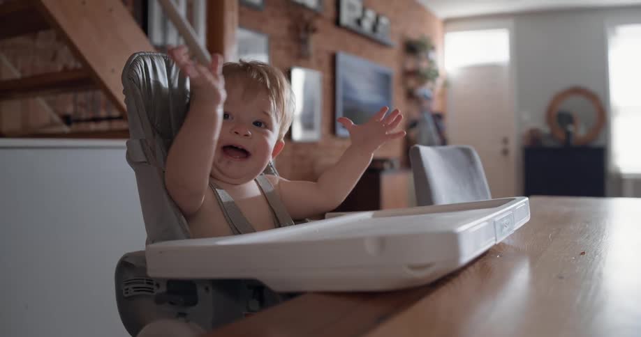 Baby sitting in a high chair clapping hands