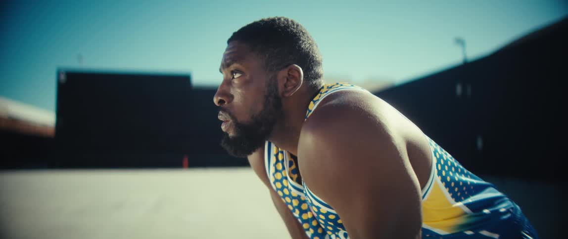 A young black man assuming a tripod standing position while outdoors after a fitness session during daytime