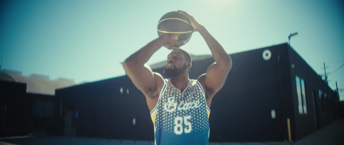 A male basketball player practices on an outdoor court on a sunny day
