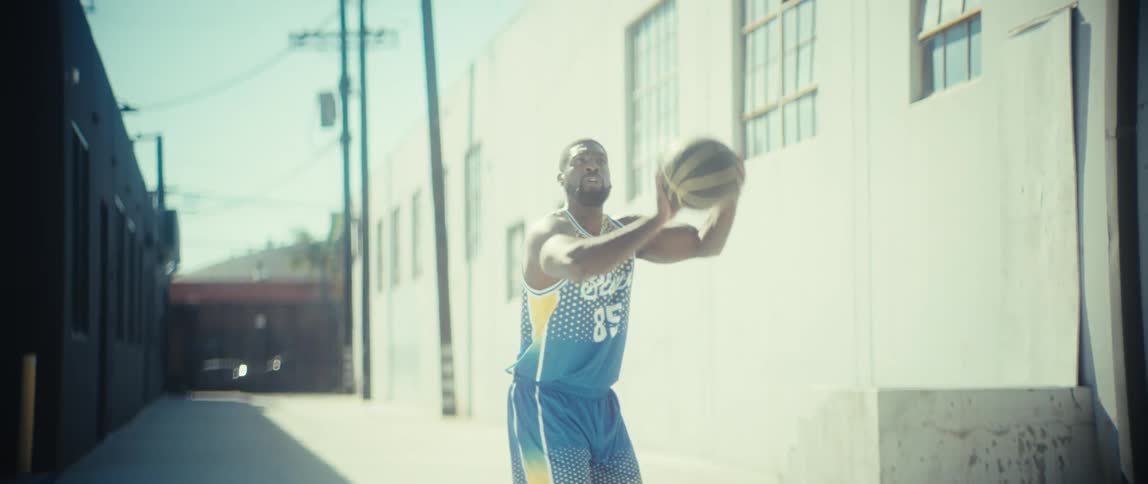 Man performing a basketball shot in an urban outdoor area