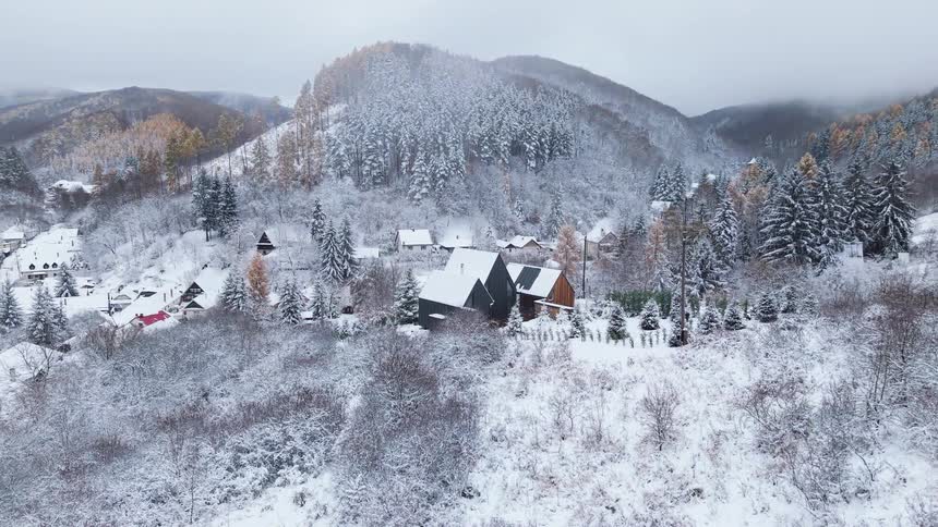 Cabins are covered with snow by the mountains