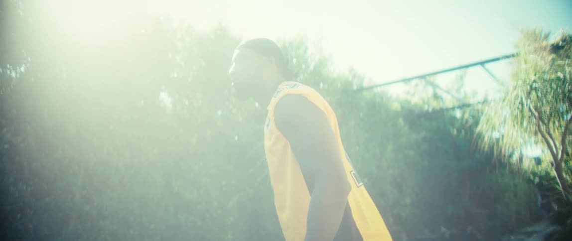 Person in yellow sports jersey in front of sunlit hedge