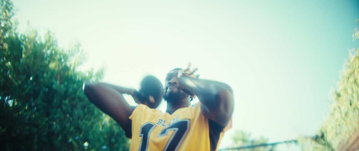 The man throws the football on a sunny day