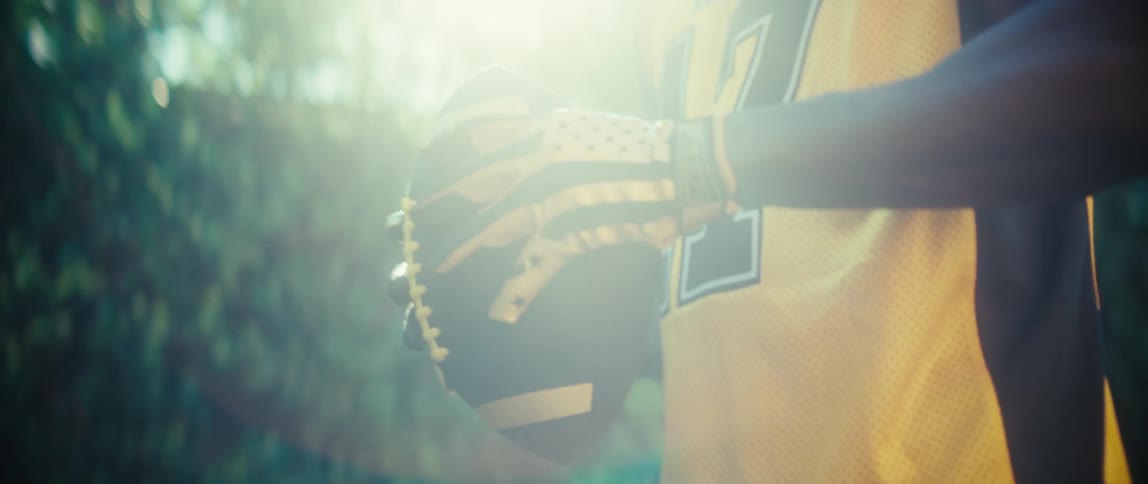 Athlete holds a basketball with both hands while wearing sports gloves outdoors