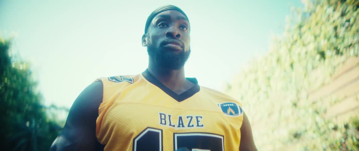 Sunlight shines on a man standing outside holding a football