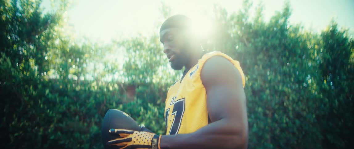 Athlete holding and playing with a sports ball outdoors while wearing uniform and gloves