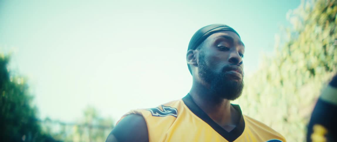 A black male athlete throwing and catching a football while standing at an outdoor court during daytime