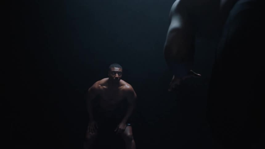 Two black man are wrestling in a darkened area