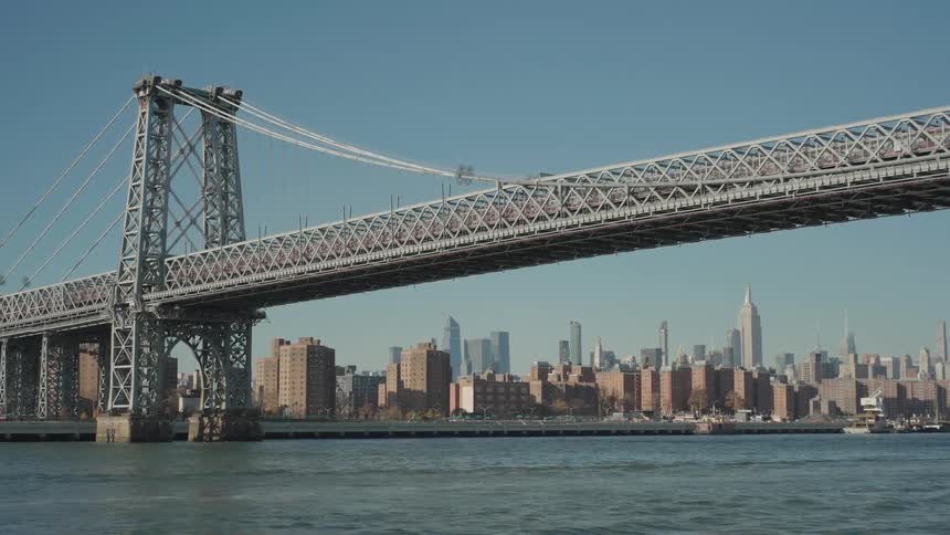 A huge suspension bridge passing over a body of water with a downtown in the background