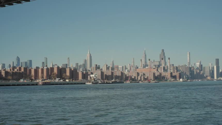 View of the urban skyline with residential buildings along the river beneath an elevated bridge