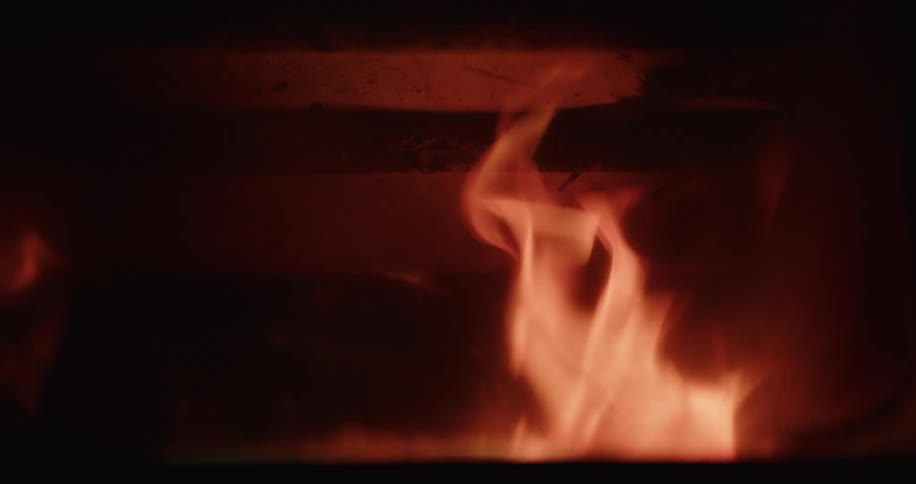 Fire burns with rapid yellow flames in a firepit at night