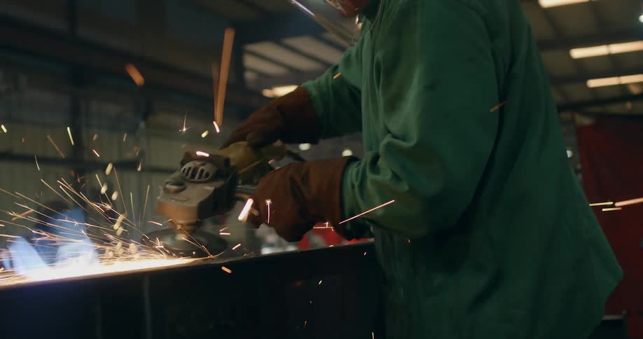 A man has a helmet on as he sands metal