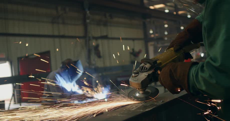 Sparks fly as welders work with tools in a workshop
