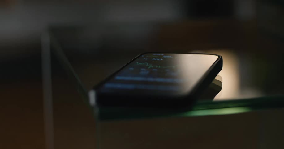 Smartphone resting on a glass surface with a financial chart displayed on the screen