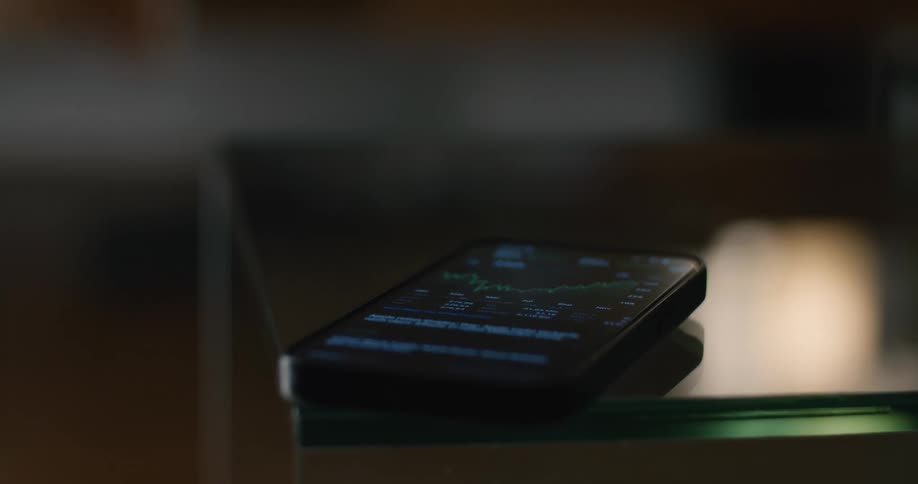 Smartphone resting on a glass surface with a financial application open on the screen