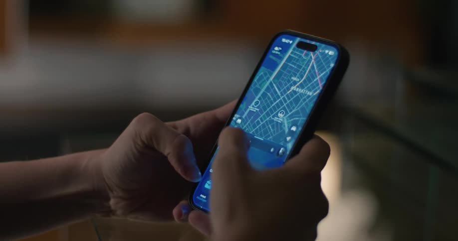 Person holding a cell phone with both hands and scrolling with their thumbs as they look at a map