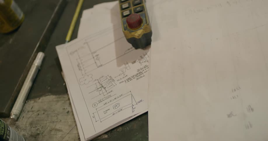 A machine control sits on top of a stack of diagrams on a table
