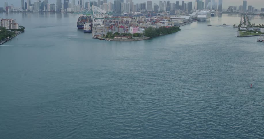 Ships sit docked on an island a distance from a slightly foggy city