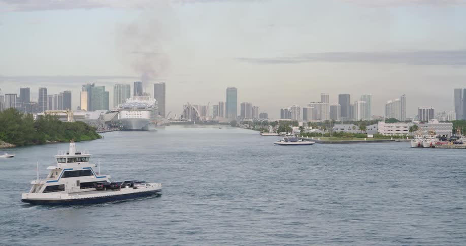 Several boats travel across the water near a coastal metropolis