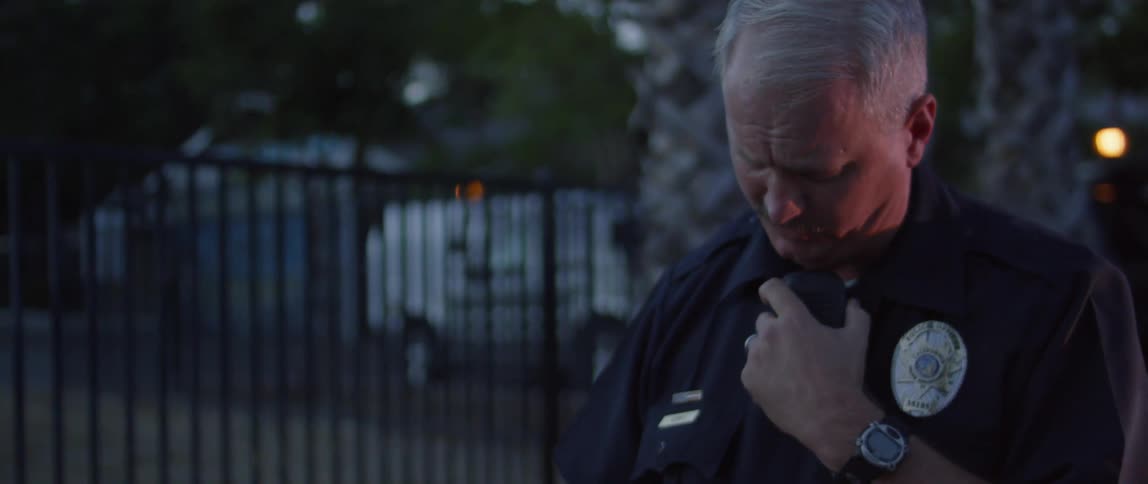 A police officer radios for help while a woman cries