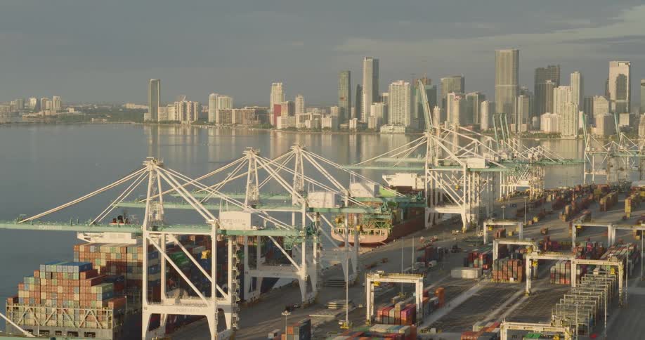Port of miami with ships laden with cargoes at sunset and distant skyscraper buildings