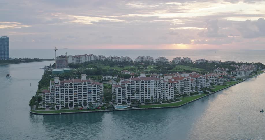 That video shows an aerial view of an exclusive residential island communityit features several large luxurious waterfront condominium buildings and a golf course or large park area further back on the island with the ocean visible in the backgroun