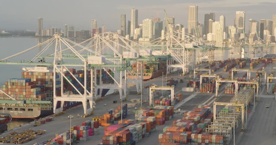 A pair of large ships are loaded with shipping crates at a shipyard