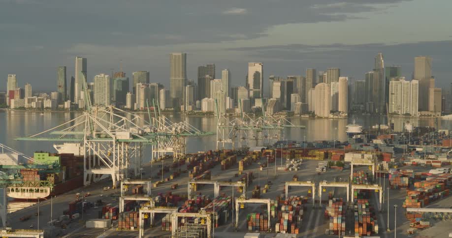 Container ship sits under the loading cranes of the loading dock while fog covers the skyline on a cloudy day