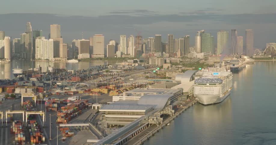 Aerial of a cruise ship and a shipping yard in a large port city