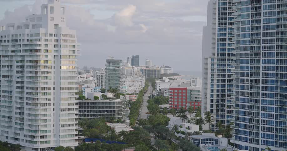 High rise apartment building with balconies overlooks other buildings on the coast