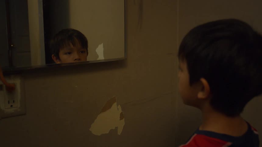 A boy looks in the mirror