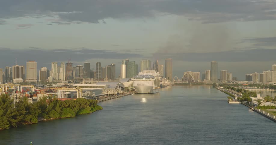 Aerial view of a cruise ship docked in a bustling metropolitan harbor at golden hour