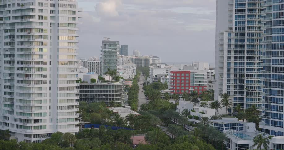 Trees line the river passing through the apartment buildings in a residential neighborhood on an overcast summer day