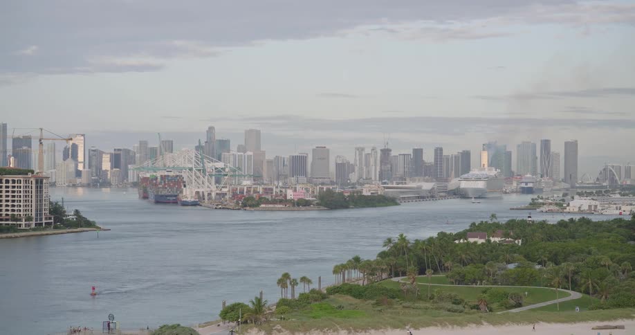 Aerial view of a coastal city skyline overlooking a calm beach beside a tranquil waterway