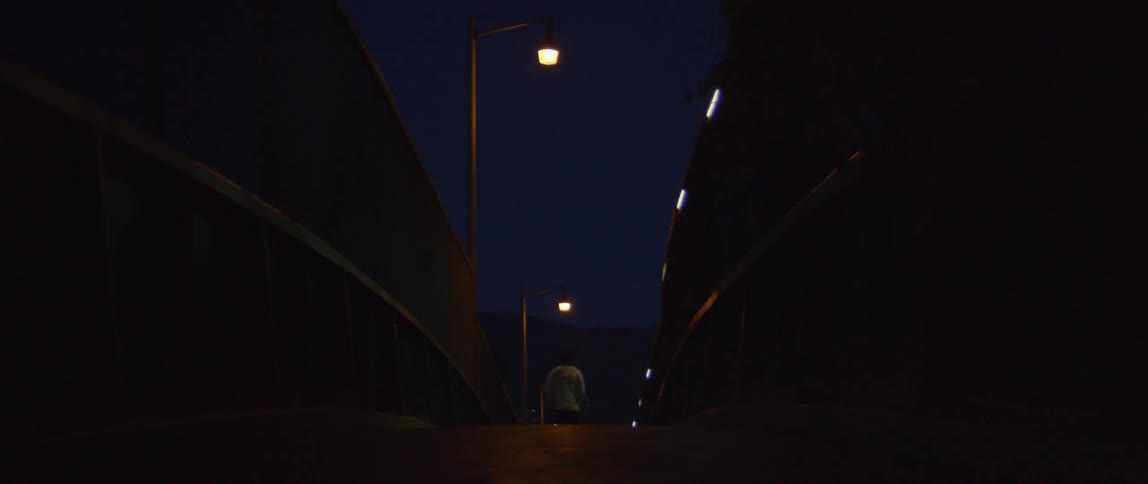 Man walks down a dimly lit street at night