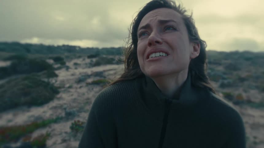 A woman cries while standing outside with a look of anguish on her face