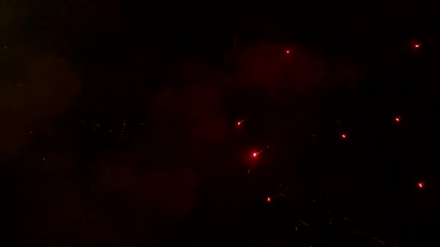 In the dark night sky a firework suddenly explodes nearby