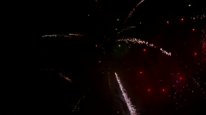 A brilliant display of fireworks illuminates the dark night sky with streaks of sparkling goldred and bursts of glowing green smoke