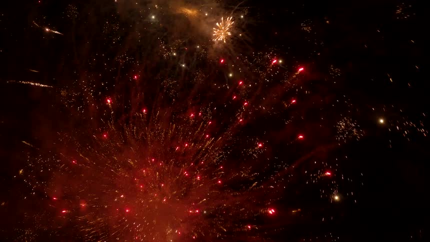 The video shows a dark night sky illuminated by bursts of fireworksthe explosions are primarily in shades of red and gold creating bright smoky patterns against the black background