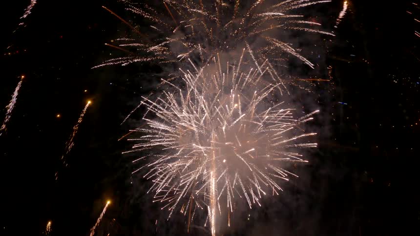 Multiple fireworks are launch into the night sky and explode