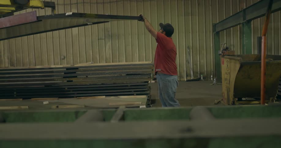 A man walks around in a shop leading a crane