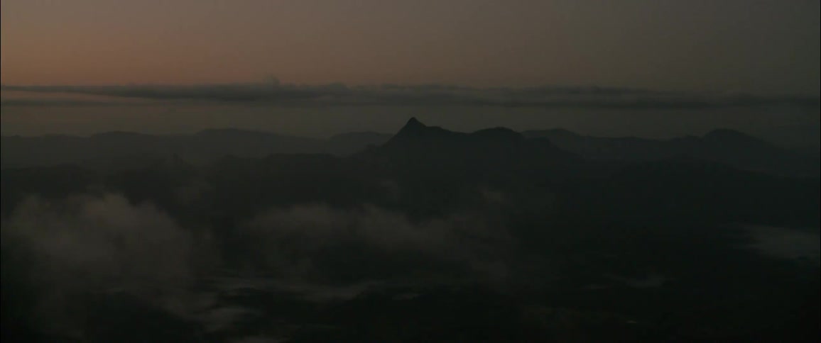 Mountain ranges appear in the distance beneath layers of mist and a dawn sky