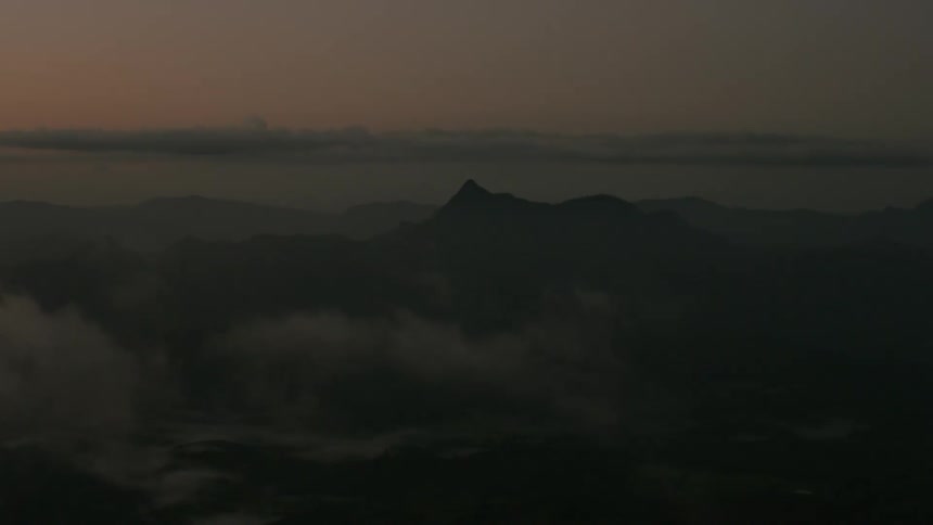 Low lying clouds and fog cover the mountains under a red sky