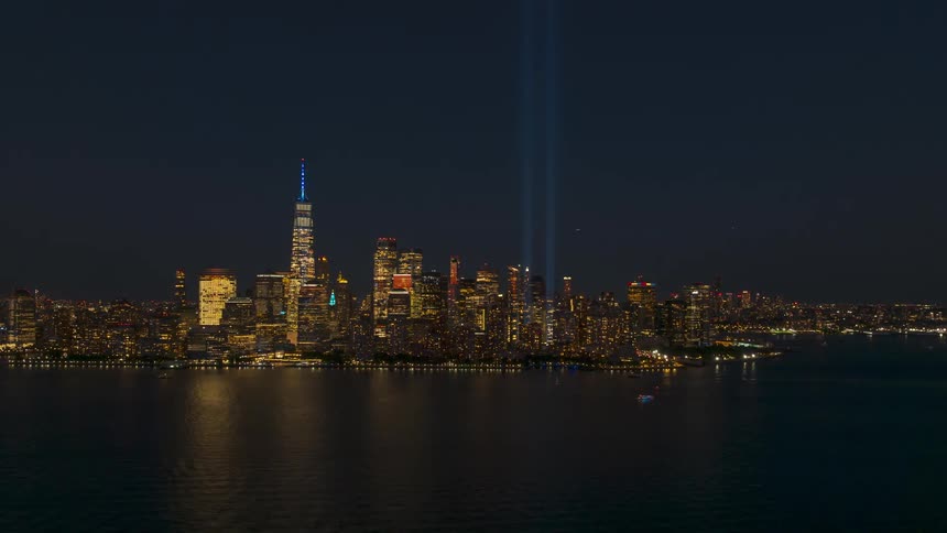 Watercraft travel through the waters off the brightly lit city skyline at night