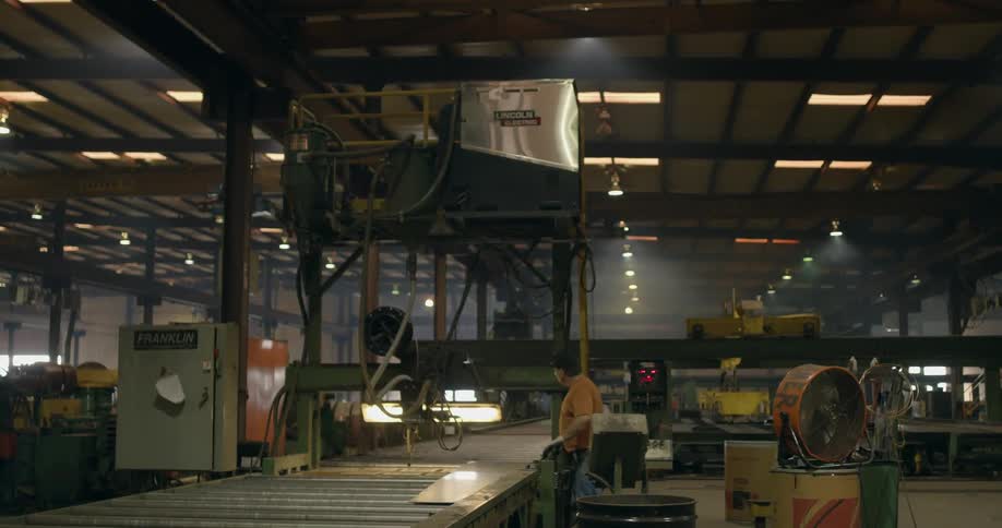 A worker hammers some steel in a warehouse