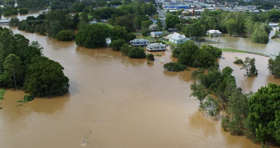 Muddy floodwaters cover a residential neighborhood of large houses on a summer day