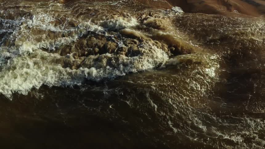 A river flows rapidly through the wilderness at midday