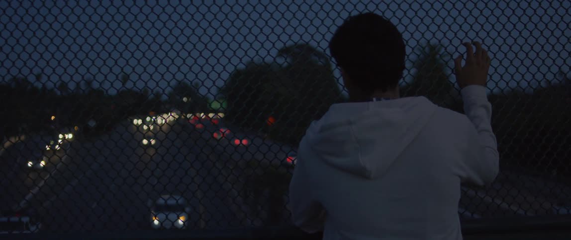 Man standing on freeway overpass watching cars drive by at night