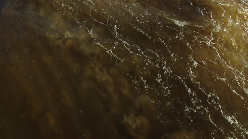 Aerial view of muddy water waves rolling in